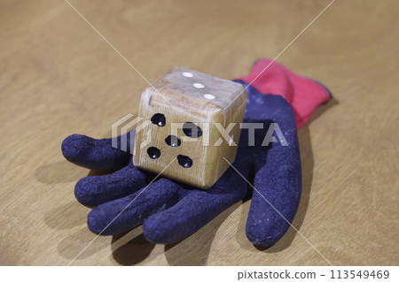 a wooden dice lies on a work glove, selective focus. Unpredictability. a wooden dice lies on a work glove, selective focus. Unpredictability. 113549469