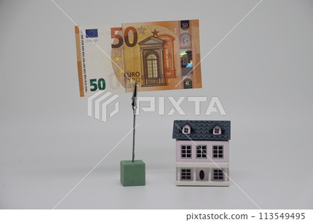 The toy house stands next to the banknote on the stand. Accurate financial calculationalculation when buying a property. The toy house stands next to the banknote on the stand. Accurate financial calculationalculation when buying a property. 113549495