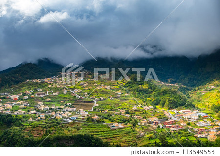 Traditional terrace village Sao Vicente, Madeira Island, Portugal. Small houses and gardens among a green mountain landscape in stormy weather. Traditional terrace village Sao Vicente, Madeira Island, Portugal. Small houses and gardens among a green mountain landscape in stormy weather. 113549553