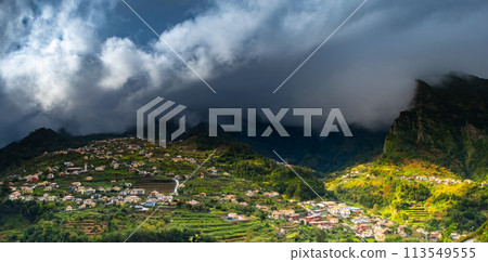 Traditional terrace village Sao Vicente, Madeira Island, Portugal. Small houses and gardens among a green mountain landscape in stormy weather. 113549555