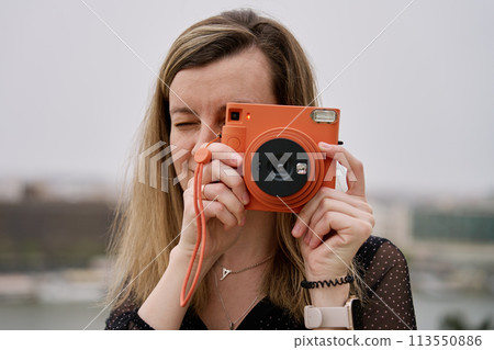 Female traveler taking picture with vintage instant camera Female traveler taking picture with vintage instant camera 113550886