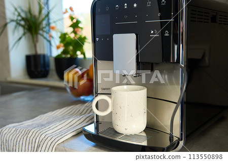 Coffee machine with cup of coffee in kitchen 113550898