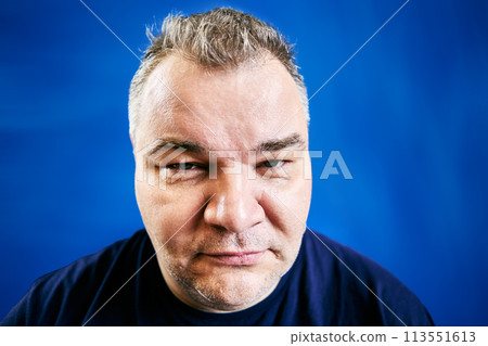 Incredulous look of European man 47 years old, close-up portrait on blue background. Incredulous look of European man 47 years old, close-up portrait on blue background. 113551613