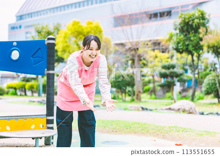 幼兒園老師在公園的遊樂場設備前與孩子們玩耍 幼兒園老師在公園的遊樂場設備前與孩子們玩耍 113551655