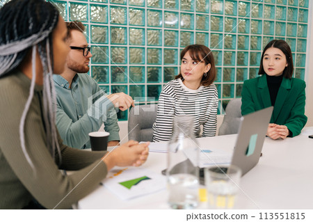 Multiracial male and female employees gathered together in boardroom or coworking space listening male team leader showing on laptop new software, explain program or shares sales growth sales. Multiracial male and female employees gathered together in boardroom or coworking space listening male team leader showing on laptop new software, explain program or shares sales growth sales. 113551815