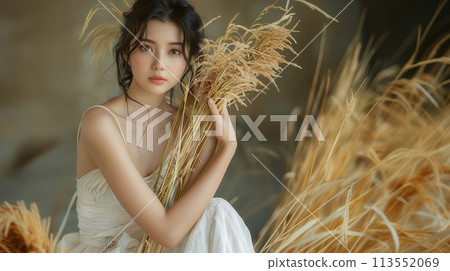 A young woman holding an ear of rice and looking straight ahead 113552069
