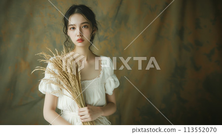 Young woman looking at camera while holding ears of rice 113552070