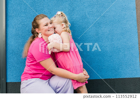 Blonde little girl with cochlear implant playing with her mother outdoor. Hear impairment deaf and health concept. Diversity and inclusion. Copy space 113552912