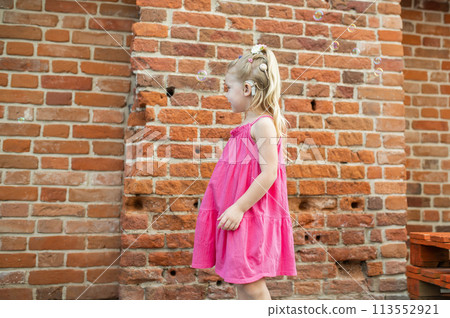 Child girl with hearing aids and cochlear implants having fun outdoor speak and playing. Copy space and empty place for advertising 113552921