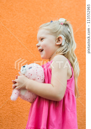 Child girl walks and have fun outdoor with cochlear implant on the head. Hearing aid and treatment concept 113552965
