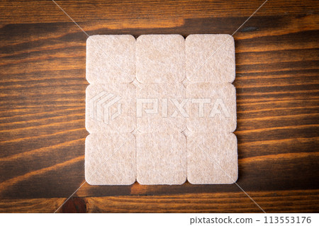 Furniture Protection Felt on a dark wood texture background Furniture Protection Felt on a dark wood texture background 113553176