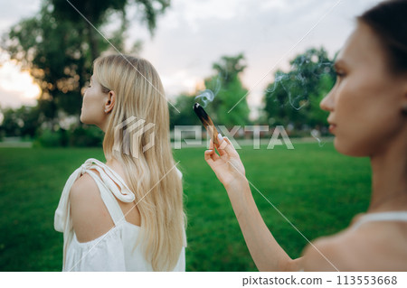 A young woman practices meditation in nature. Meditation with smoke. A young woman practices meditation in nature. Meditation with smoke. 113553668