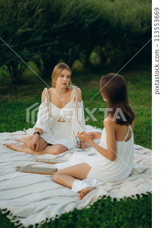 Meditation and nailing. Two young women are meditating in nature. Meditation and nailing. Two young women are meditating in nature. 113553669