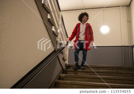 Guy in red jacket going downstairs and looking aside 113554055