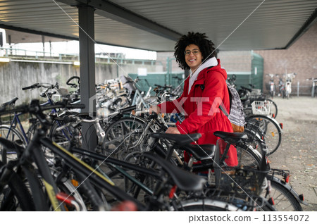 Smiling curly-haired guy renting a bike and looking contented 113554072