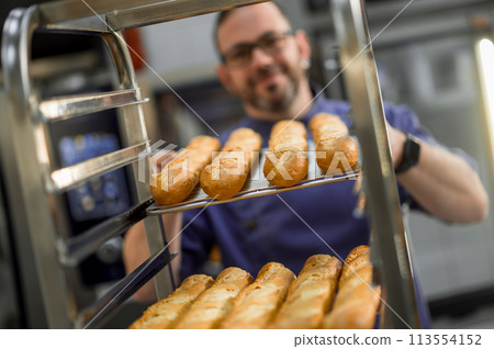 Professional baker at bakery with bread baguette 113554152