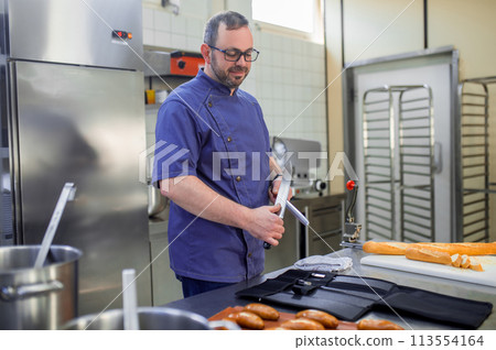 Man in eyeglasses working in the kitchen and looking involved 113554164