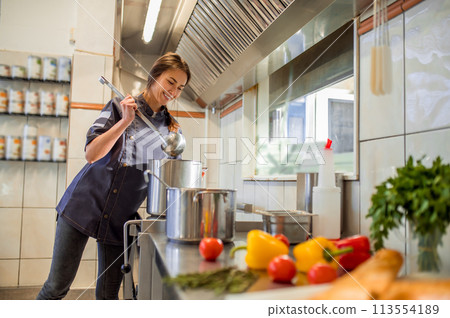 Smiling young cooker in the kitchen looking busy 113554189