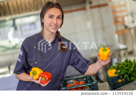Young smiling woman with peppers in hands in the kitchen 113554239