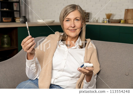 Smiling mature caucasian diabetic woman with insulin syringe in hands 113554248