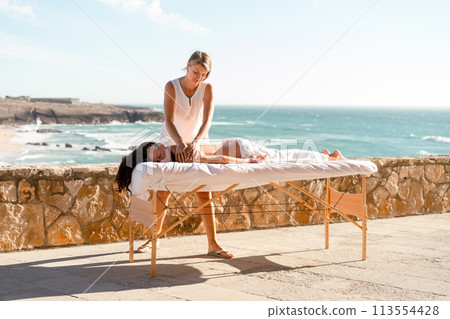 Professional female masseur giving massage client 113554428