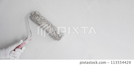 Painting the wall with a roller with white paint. Painting a bare wall with a roller with white paint. Apartment painting, renovation using white paint 113554429