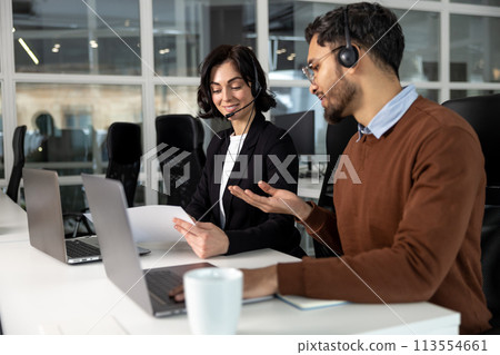 Business partners sitting at table in boardroom working on project with laptops Business partners sitting at table in boardroom working on project with laptops 113554661
