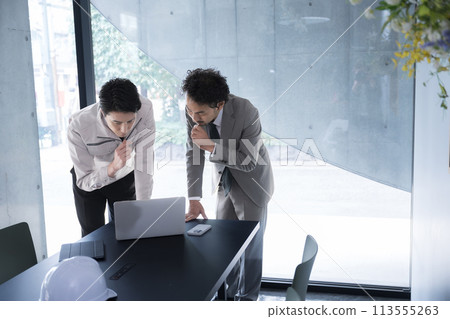 A site supervisor and construction management engineer checking the construction drawings. A bird's-eye view of a businessman thinking and worrying about building design and construction management. 113555263
