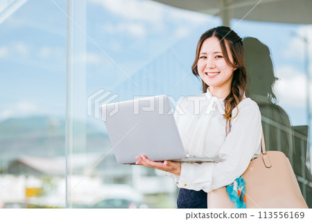 Office casual office worker/business woman using a laptop in a business district 113556169