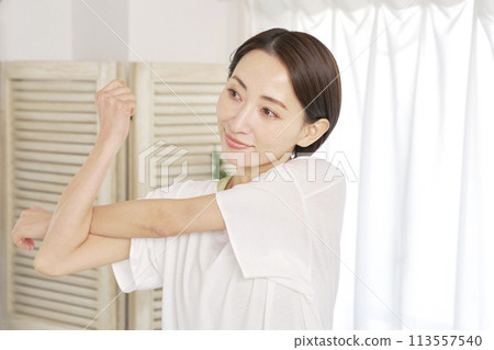 一名 40 多歲的婦女在家中伸展雙臂 113557540