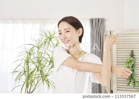 A woman in her 40s stretching her arms at home 113557567