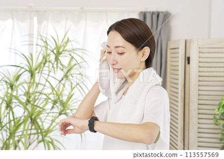 一位 40 多歲的女性在家運動並使用智慧手錶 113557569