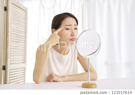 Middle-aged woman suffering from wrinkles around the eyes Middle-aged woman suffering from wrinkles around the eyes 113557614