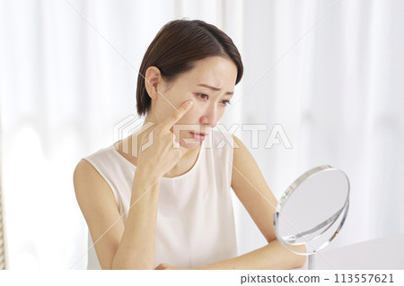 Middle-aged woman suffering from wrinkles around the eyes Middle-aged woman suffering from wrinkles around the eyes 113557621