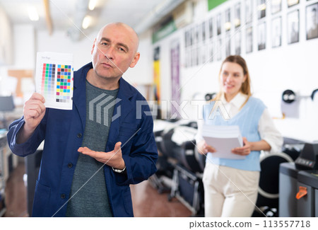 Service engineer demonstrating test page with color palette in his hand 113557718