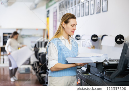 Technician operator changes paper on printer plotter machine 113557808