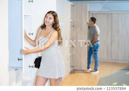 Happy female shopper chooses a wardrobe in furniture store 113557894