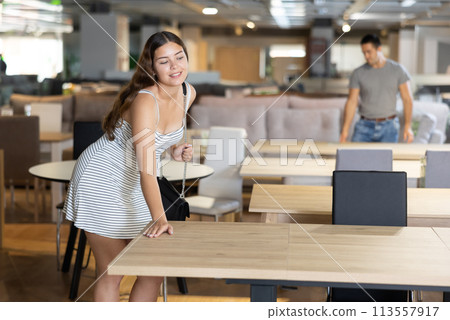 In furniture showroom,woman inspects sliding kitchen table In furniture showroom,woman inspects sliding kitchen table 113557917