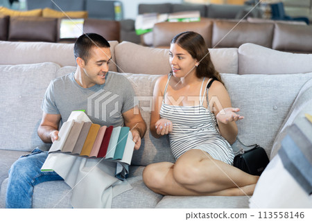 Smiling couple is choosing modern materials for furniture for their home in store 113558146