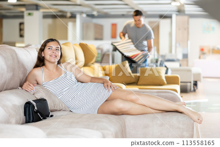 Smiling girl lying on sofa dreaming about buying in furniture store 113558165