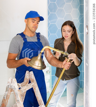 Landlady consults with a professional builder about installing a new shower in remodeling bathroom. 113558166
