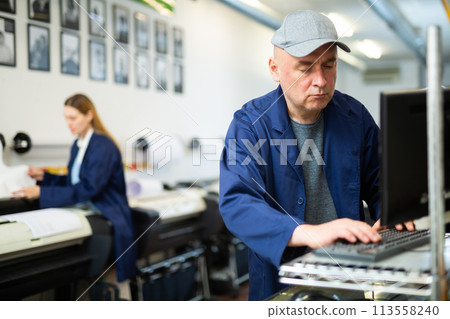 Male printing facility worker using computer 113558240