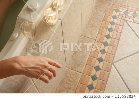 Woman Relaxing in the Bathroom Spa Tub with a Glass of Sparkling Champagne and Candles. Woman Relaxing in the Bathroom Spa Tub with a Glass of Sparkling Champagne and Candles. 113558824