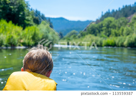 Selective focus on a child rafting down the wild and scenic Rogue River while wearing a life jacket 113559387