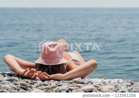 Unrecognizable positive woman in white bikini sunbathing or tanning on seaside beach during summer. happy tourist enjoying sun tan lying on beach chair lounge at luxury resort 113561208
