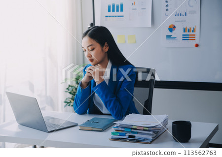 Asian woman feeling migraine head strain.Overworked businesswoman financier while working on laptop and tablet at modern office. Asian woman feeling migraine head strain.Overworked businesswoman financier while working on laptop and tablet at modern office. 113562763