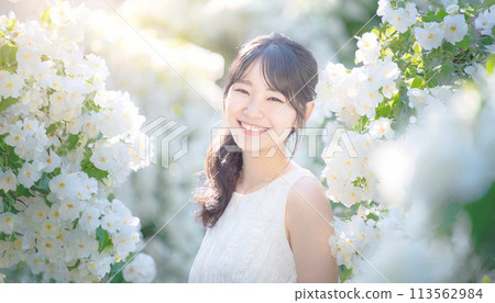 戶外微笑的年輕女子被白色盛開的花朵包圍 113562984