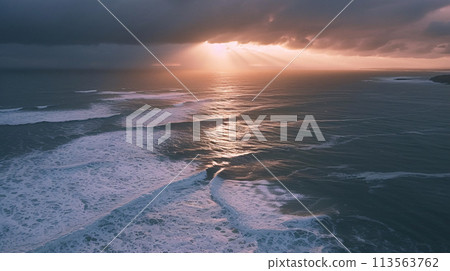 Moody Aerial Landscape Depict a dramatic aerial view of a vast coastline during a stormy sunset 113563762