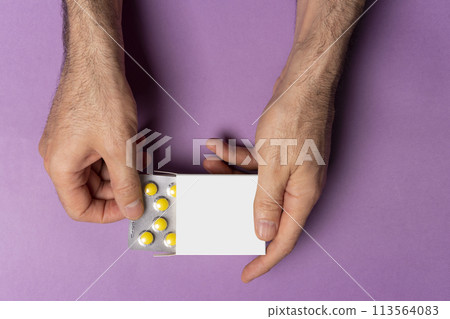 Male hand bringing out pills tablet from box in front of purple background mock-up series  113564083