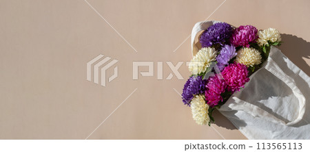 Mixed colorful flowers in cotton bag. Creative minimalistic flowers. Concept of holiday celebrating present and gift. Bouquet delivery Mixed colorful flowers in cotton bag. Creative minimalistic flowers. Concept of holiday celebrating present and gift. Bouquet delivery 113565113